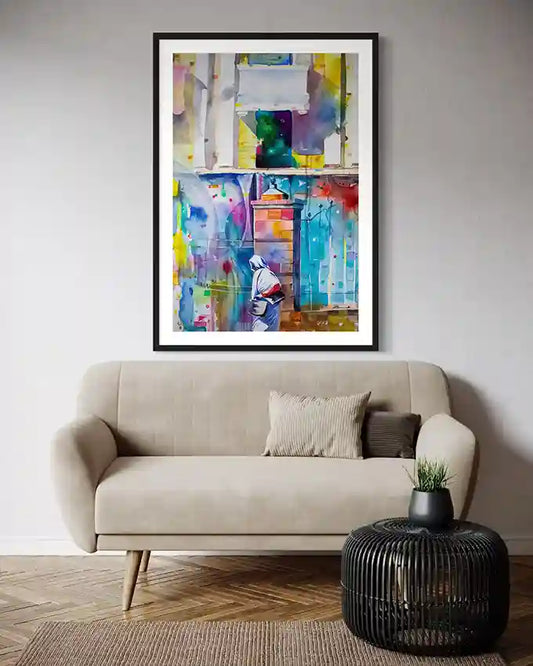 Colorful framed abstract print of A Sudanese woman on wall above beige sofa with a black side table. Artist Galal Yousif