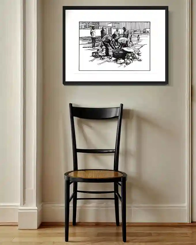 Community Kitchen art print by Obada Gabir displayed in black frame above wooden chair in modern dining room interior